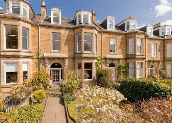 Stately house with a well-maintained garden on a clear day