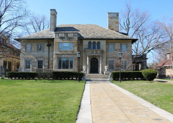 Stately stone house with a well-maintained lawn and driveway